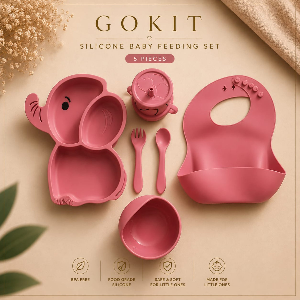 A 5-piece pink silicone baby feeding set by GOKIT, including an elephant-shaped divided plate, a small cup, a spoon, a fork, and a bib, arranged on a beige background with decorative dried flowers and a gold ribbon.